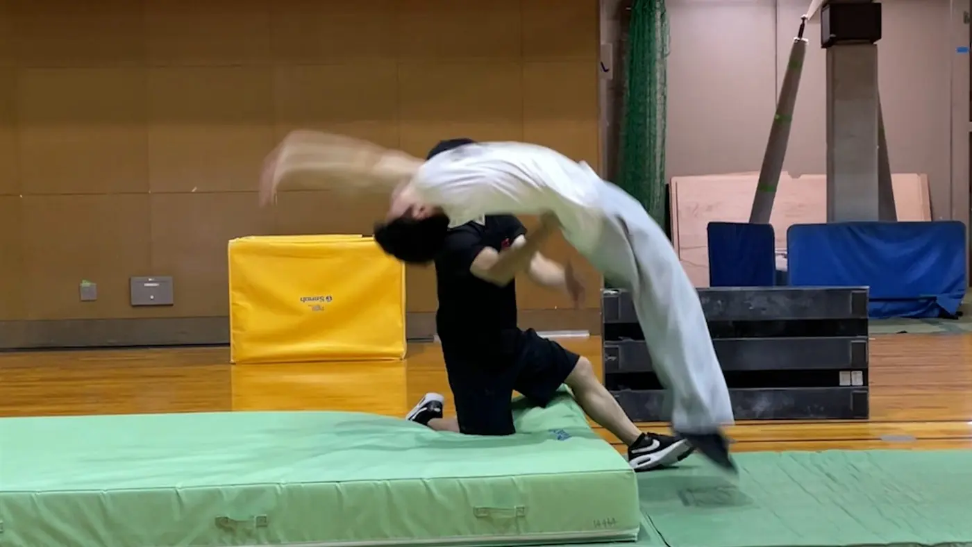 講師が受講者のバク転を補助しているレッスン風景