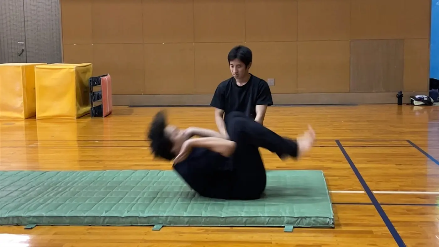講師がマット上で受講者の動きを確認している様子