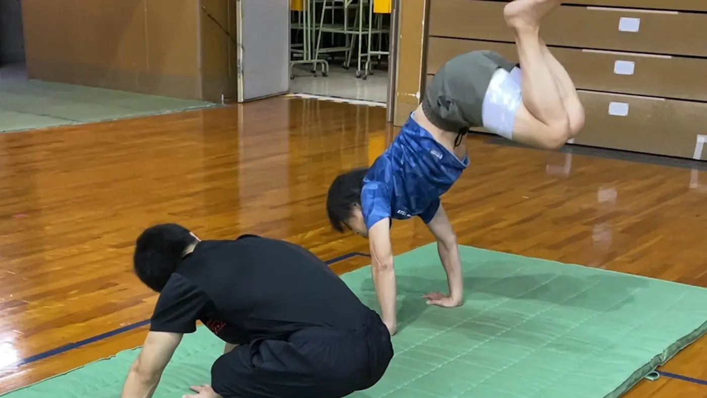 講師がそばで見守りながら倒立を練習している様子