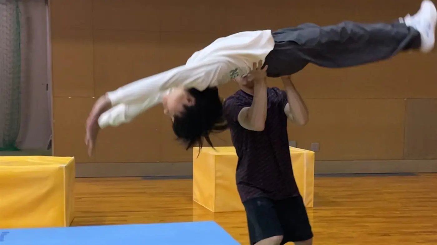 講師が受講者の回転動作を補助している様子