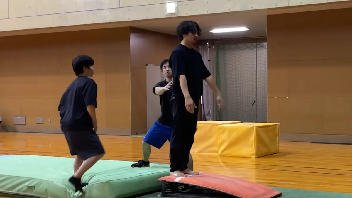 補助を受けながらバク転レッスンに挑戦している様子